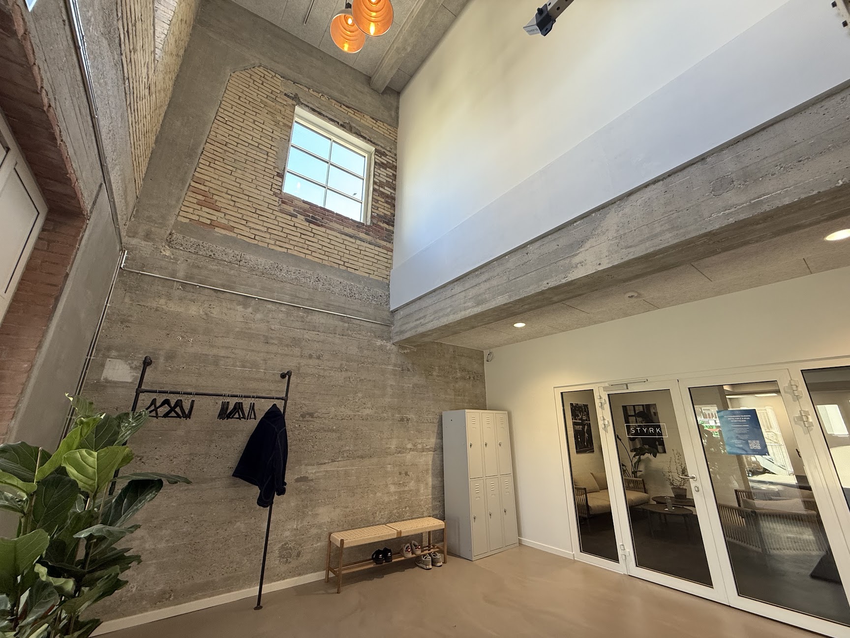 Indgangsområde i Meiers Gym på Østerbro 5C i Odense med rå beton, mursten og varme lamper